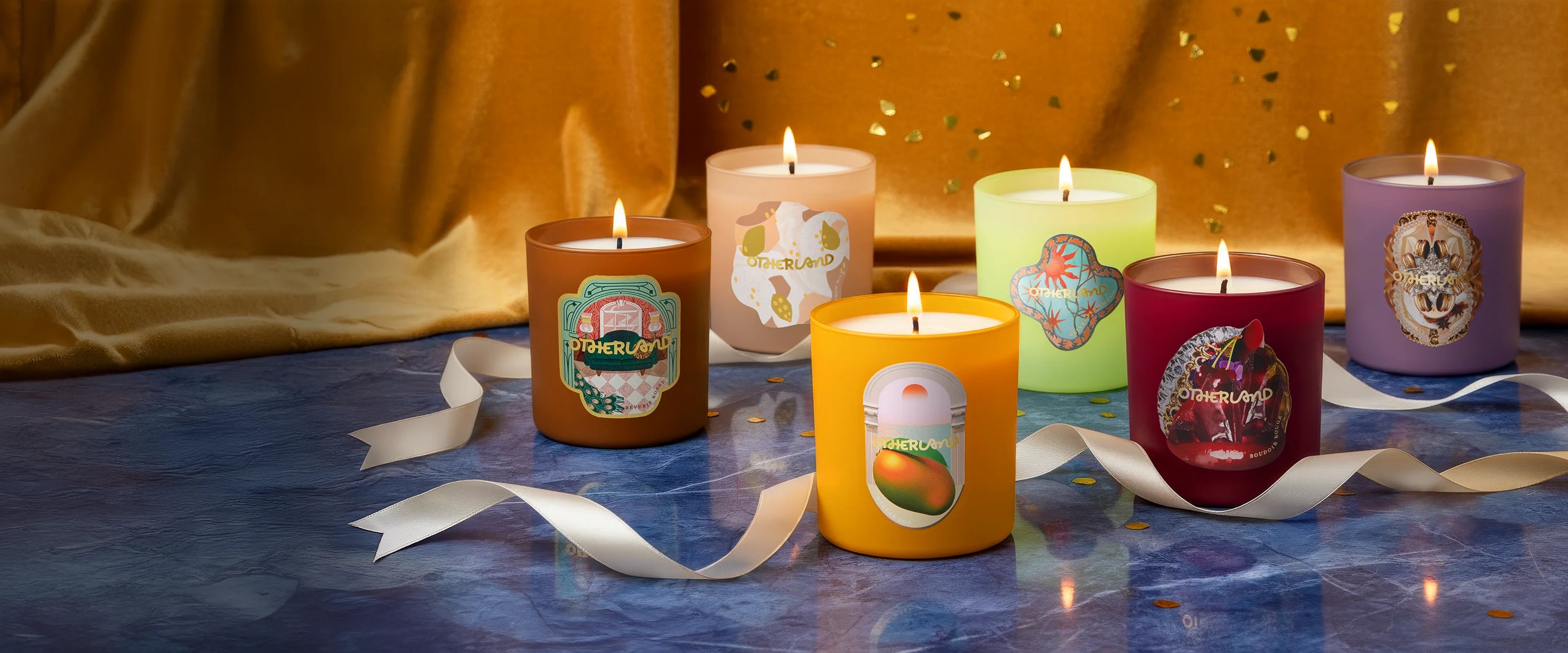 Row of colorful candles with decorative labels on a blue surface.