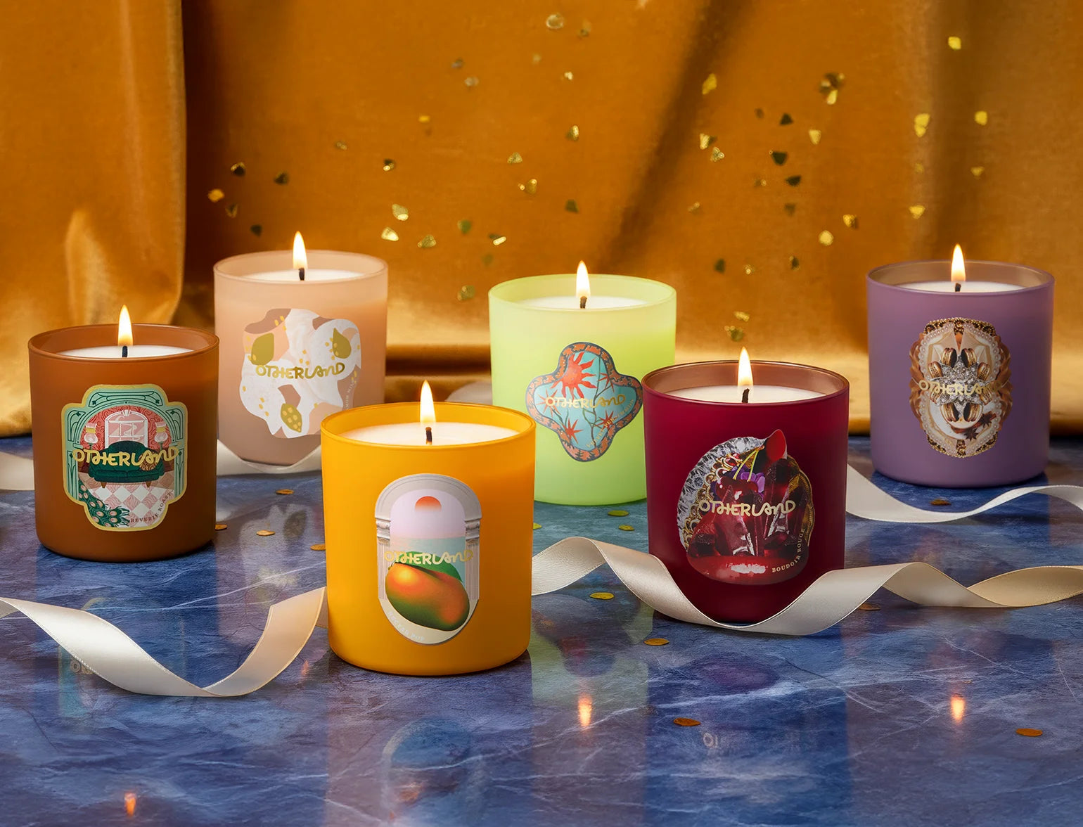 Set of colorful candles with decorative labels on a reflective surface.
