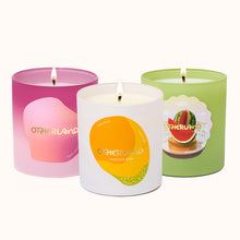 Three candles with colorful labels and 'Otherland' branding on a white background