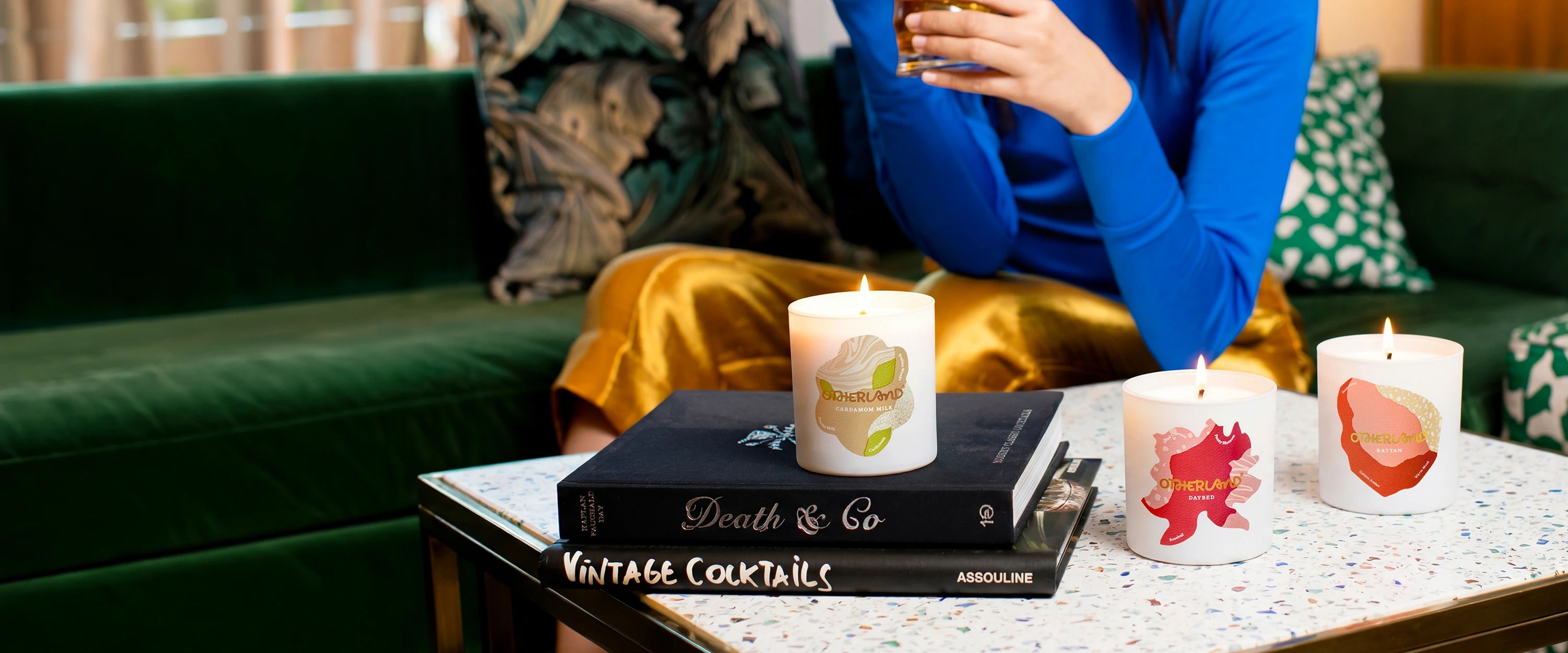Person sitting on a couch with candles and books on a coffee table