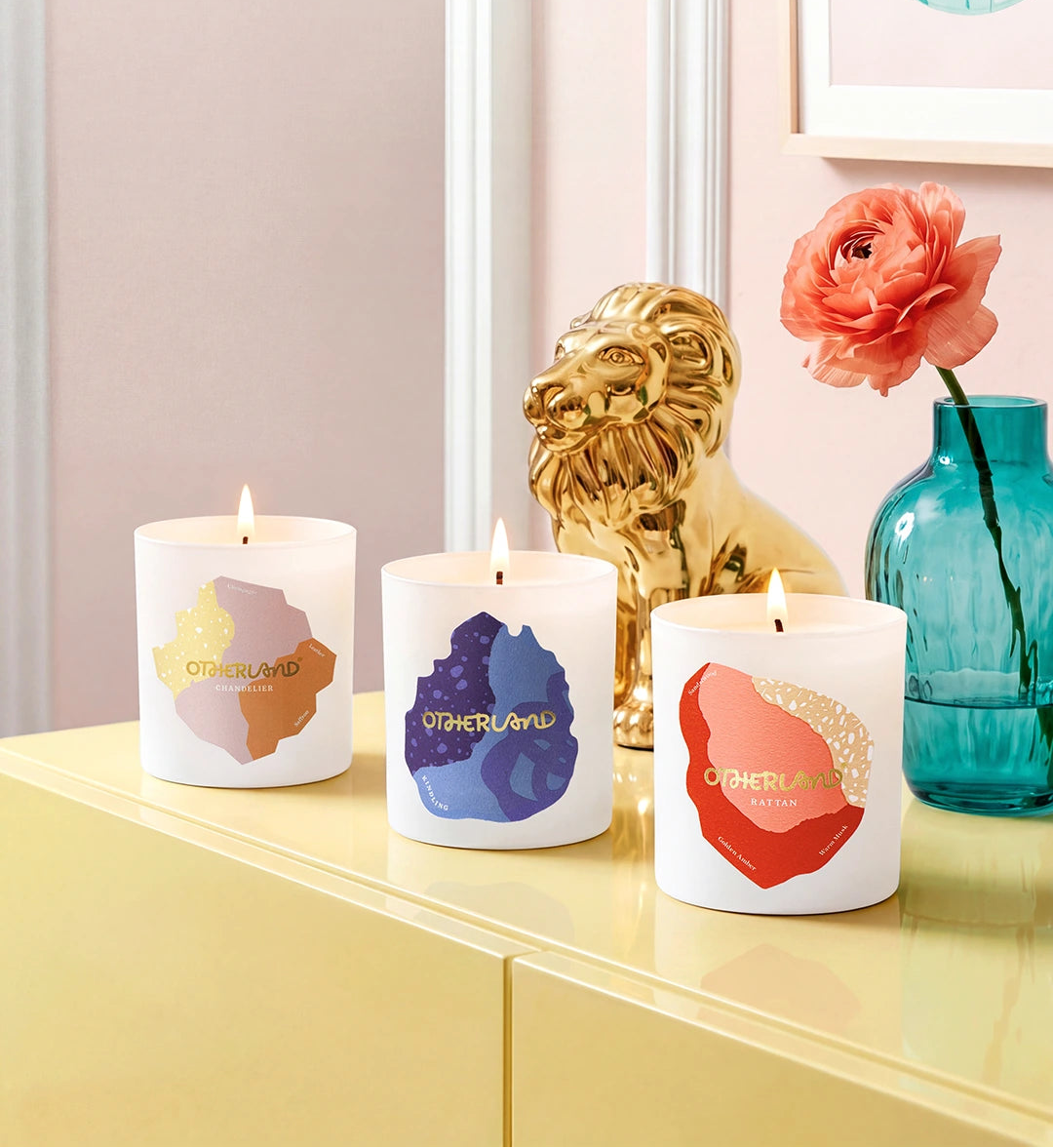 Three candles with colorful designs on a shelf with decorative items.