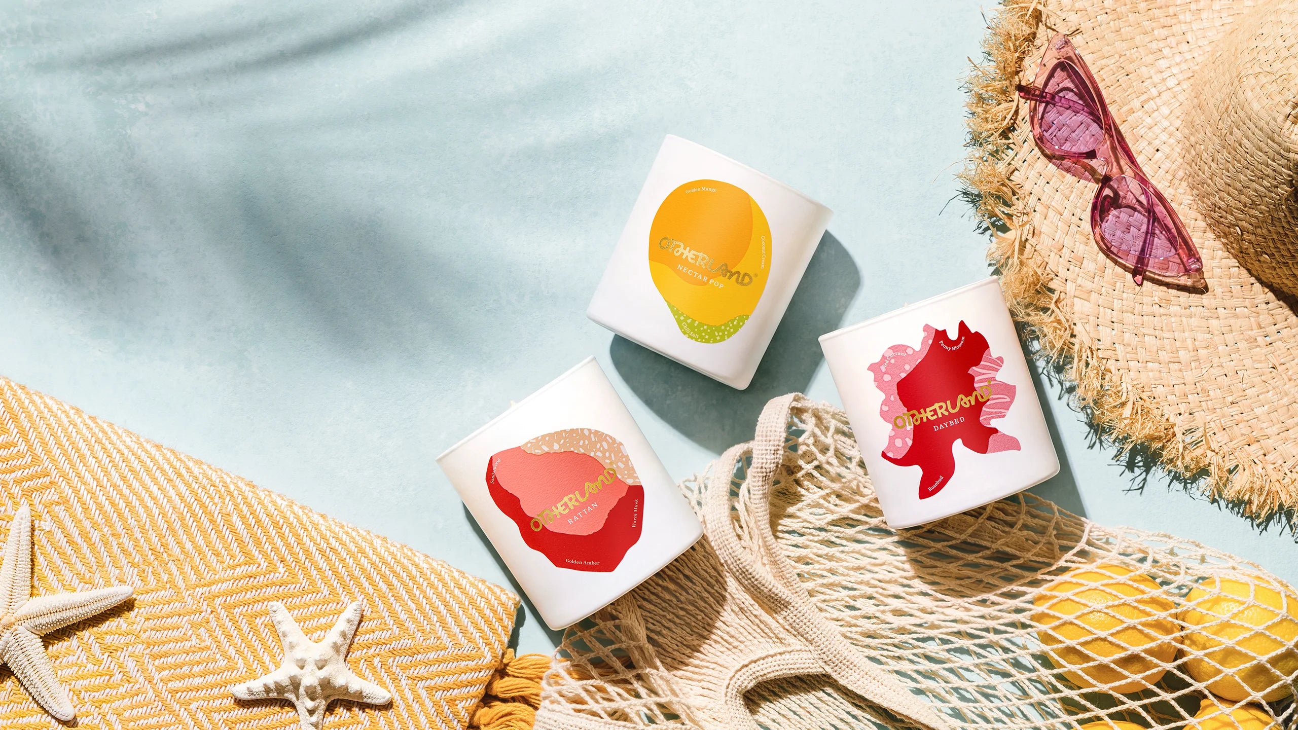 Three small boxes with colorful designs on a light blue surface with beach-themed items.