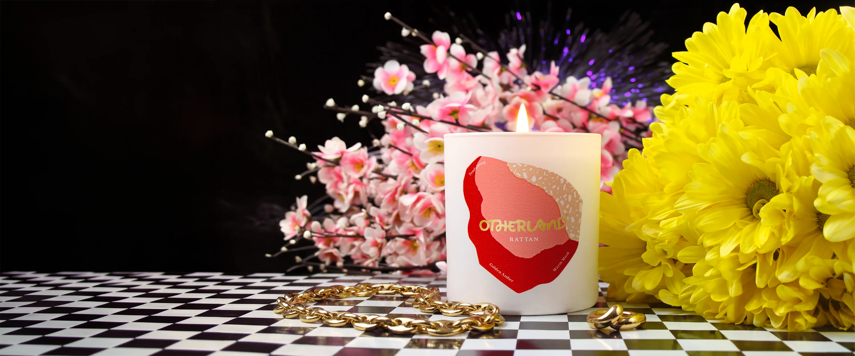 Candle with a heart design surrounded by flowers on a checkered surface