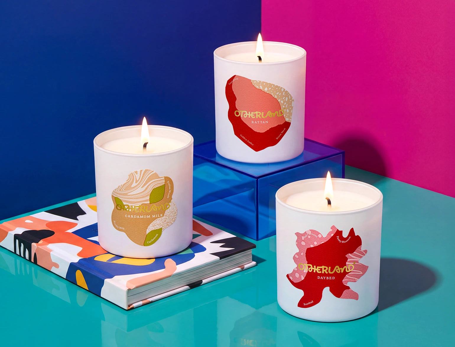 Three lit candles with colorful designs on a vibrant background