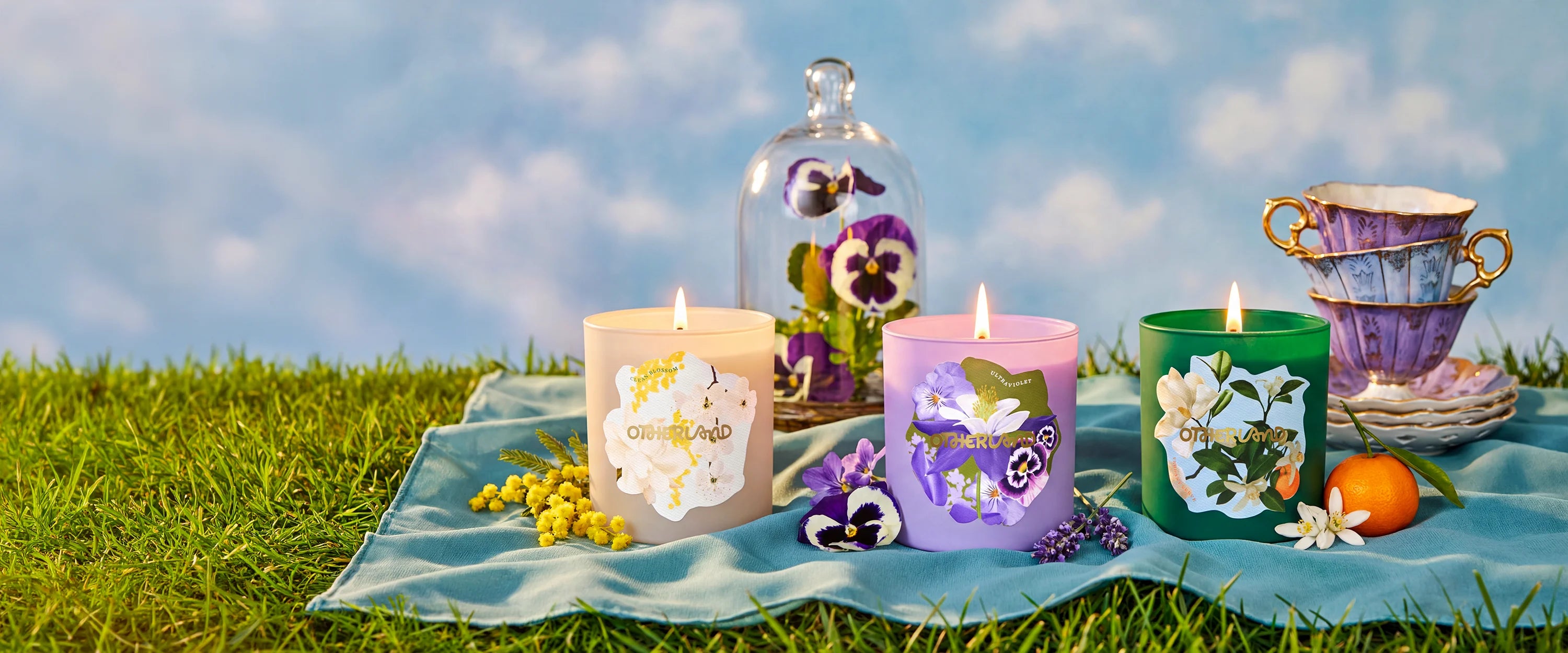 Decorative candles with floral designs on a grassy field with a clear blue sky.