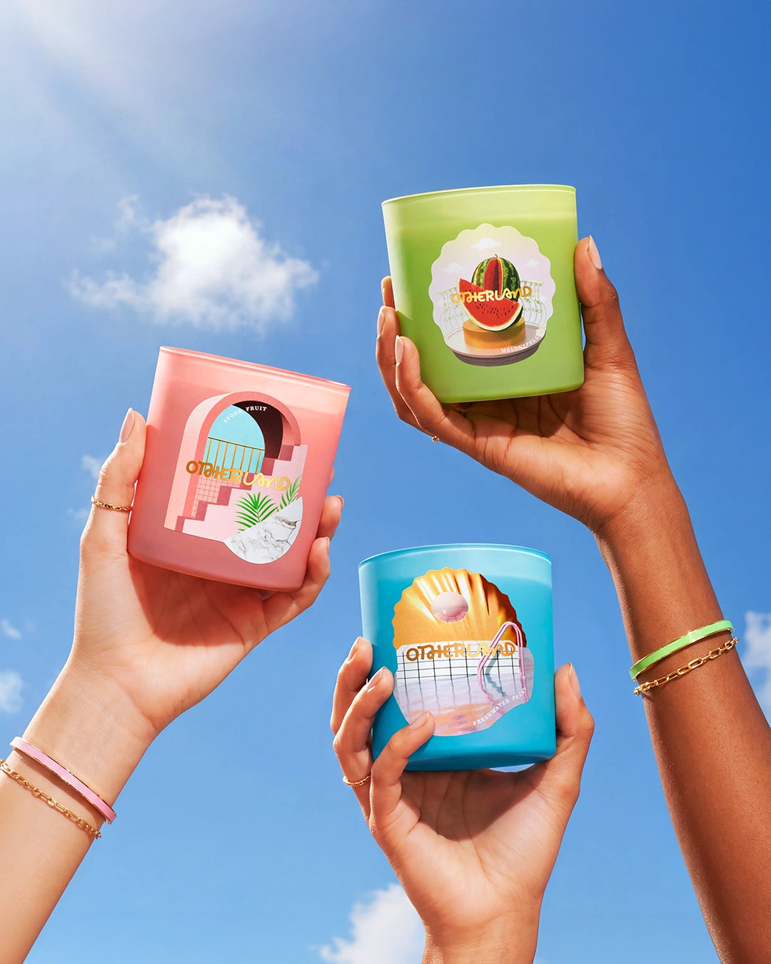 Three colorful candles held by hands against a blue sky.
