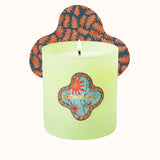 Green candle with a decorative lid featuring abstract designs on a white background