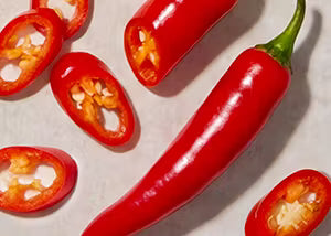 Red chili peppers and sliced chili peppers on a light background