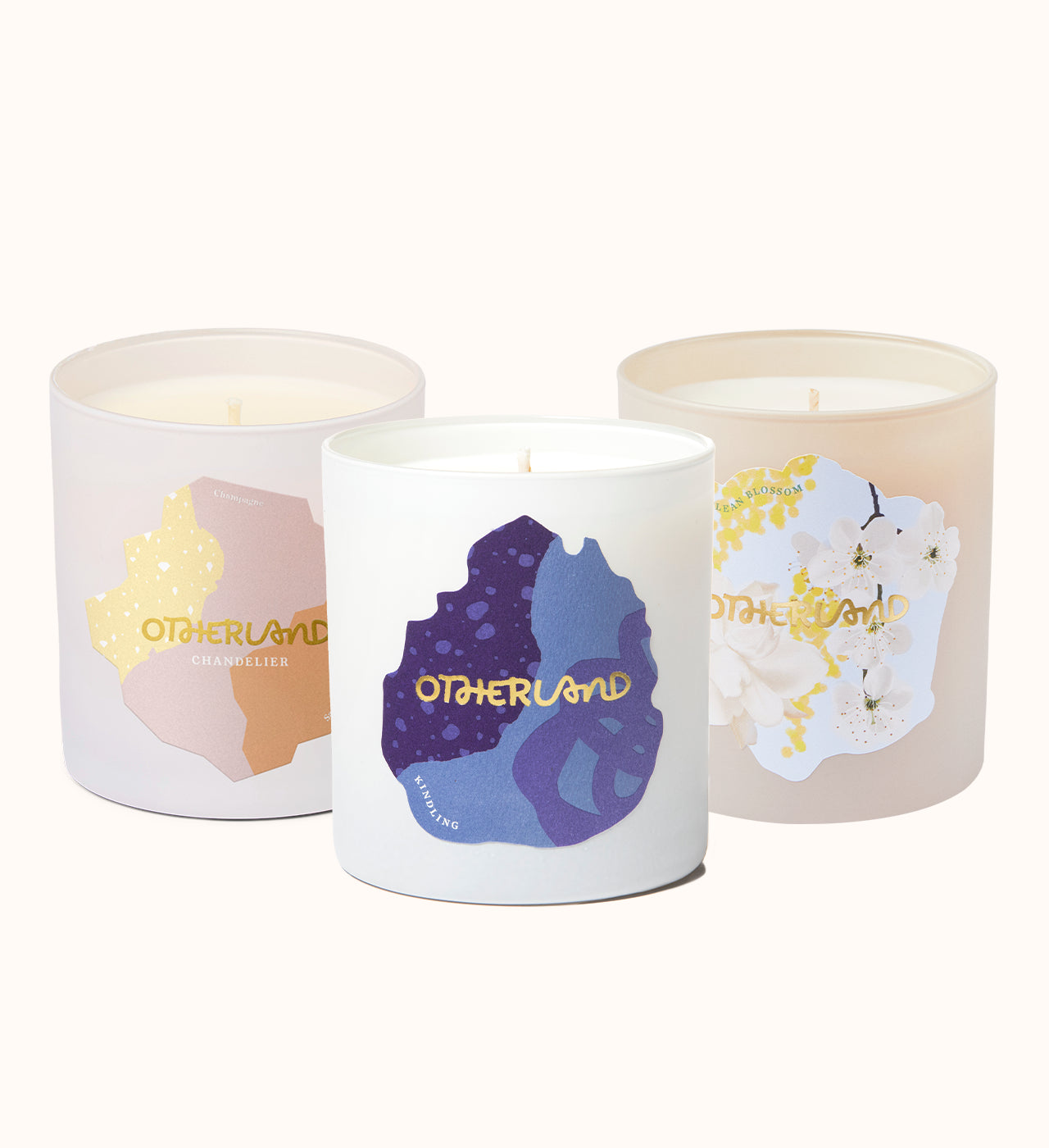 Three candles with colorful labels and 'Otherland' branding on a white background