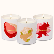Three scented candles with colorful labels on a white background