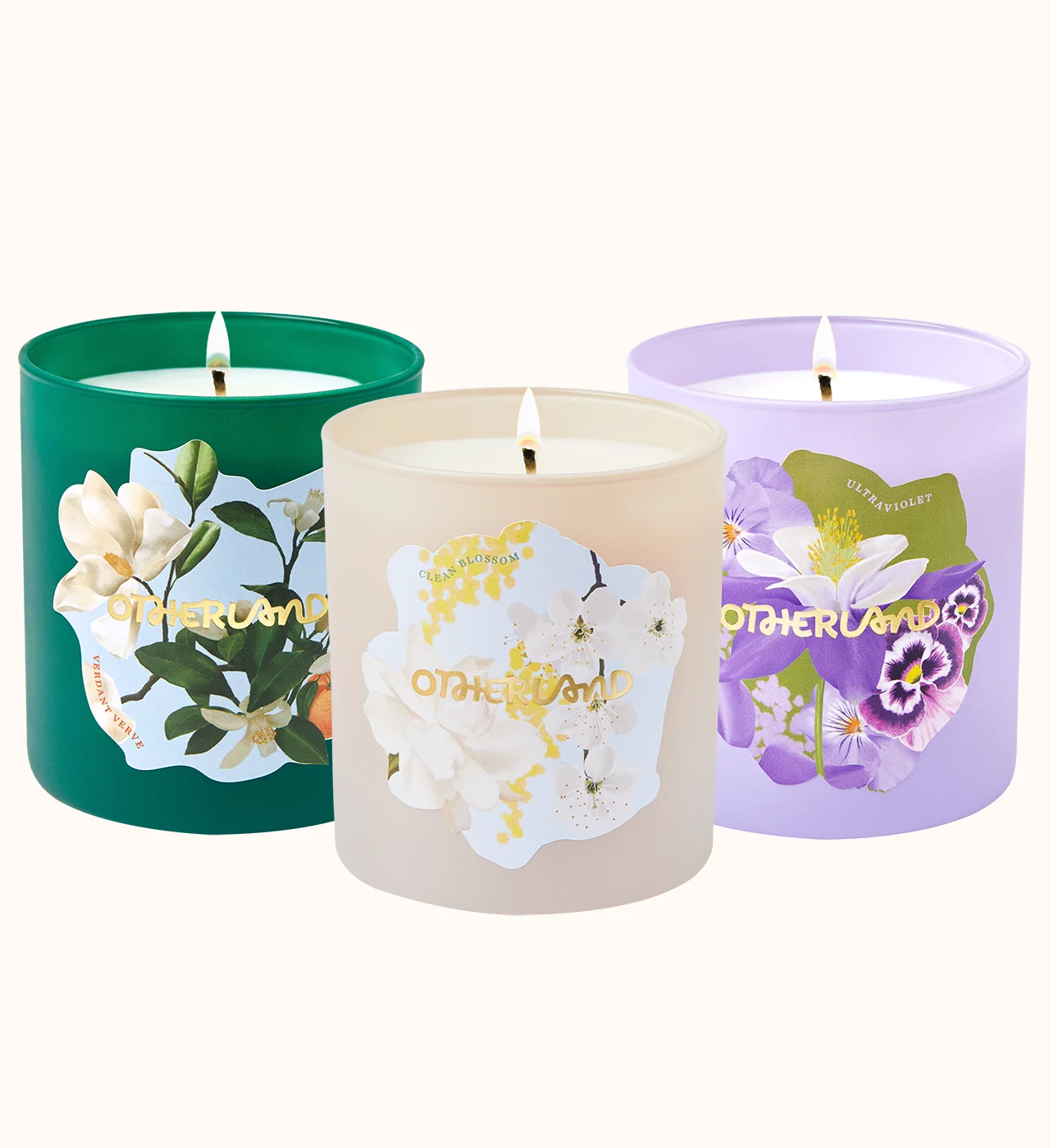 Three scented candles with floral designs on their containers against a white background.