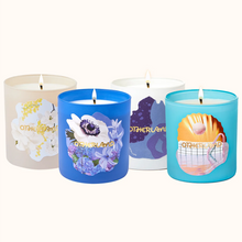 Four lit candles with colorful labels on a white background