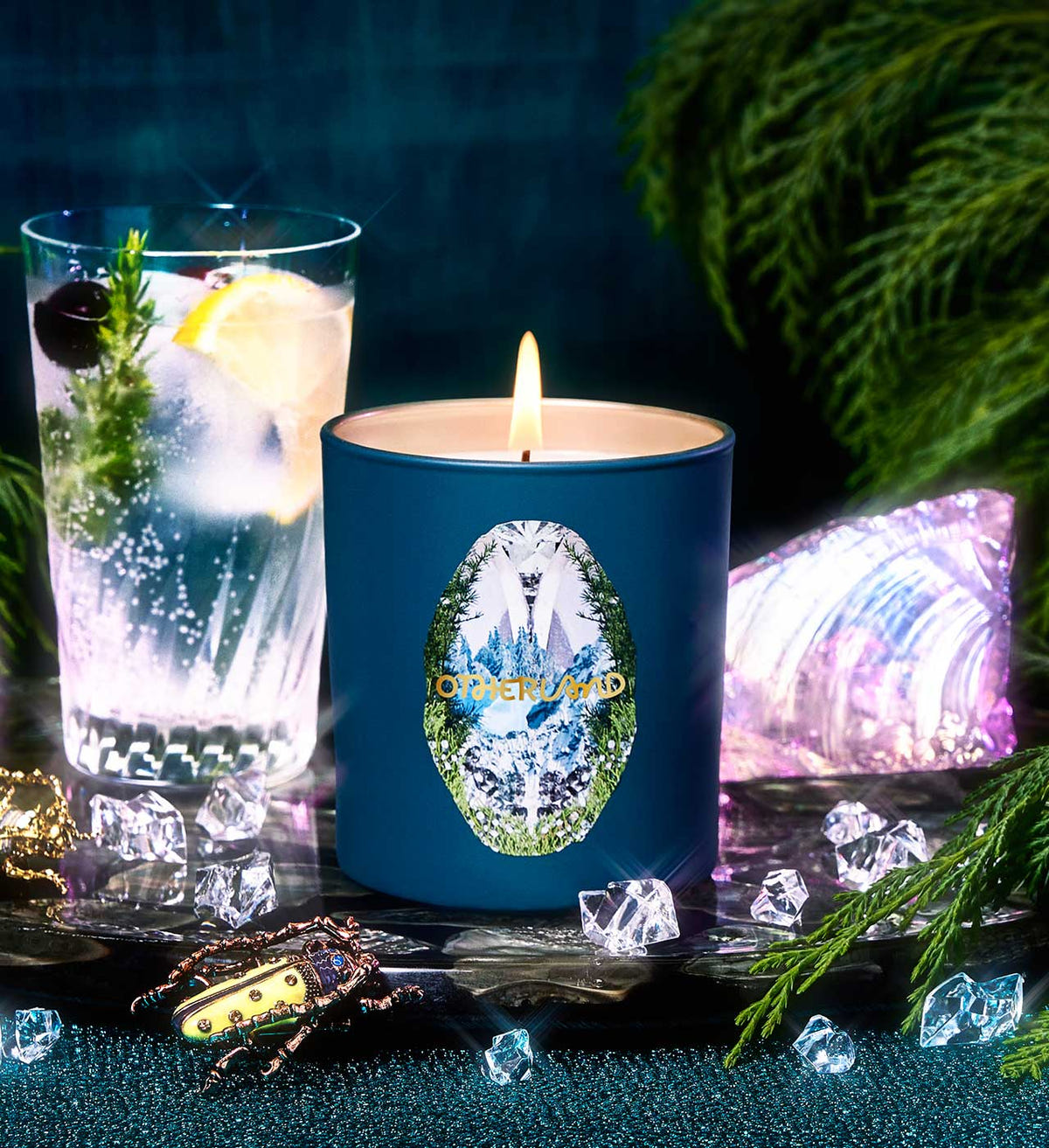 Blue candle with a decorative label next to a glass of water and ice, with a dark background and decorative elements.