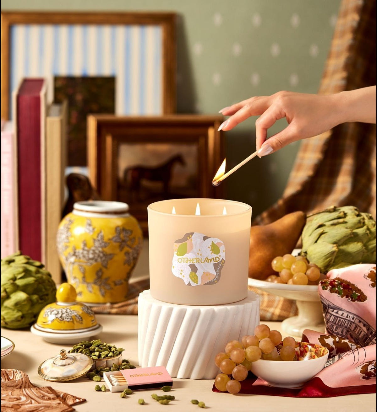 Hand lighting a candle with decorative items around
