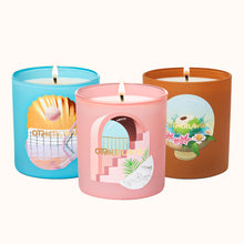 Three candles in colorful tins with artistic designs on a white background
