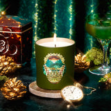 Green candle with a decorative label on a dark surface with decorative items.