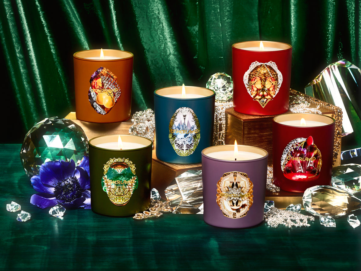 Set of six lit candles with decorative covers on a green surface with crystals.